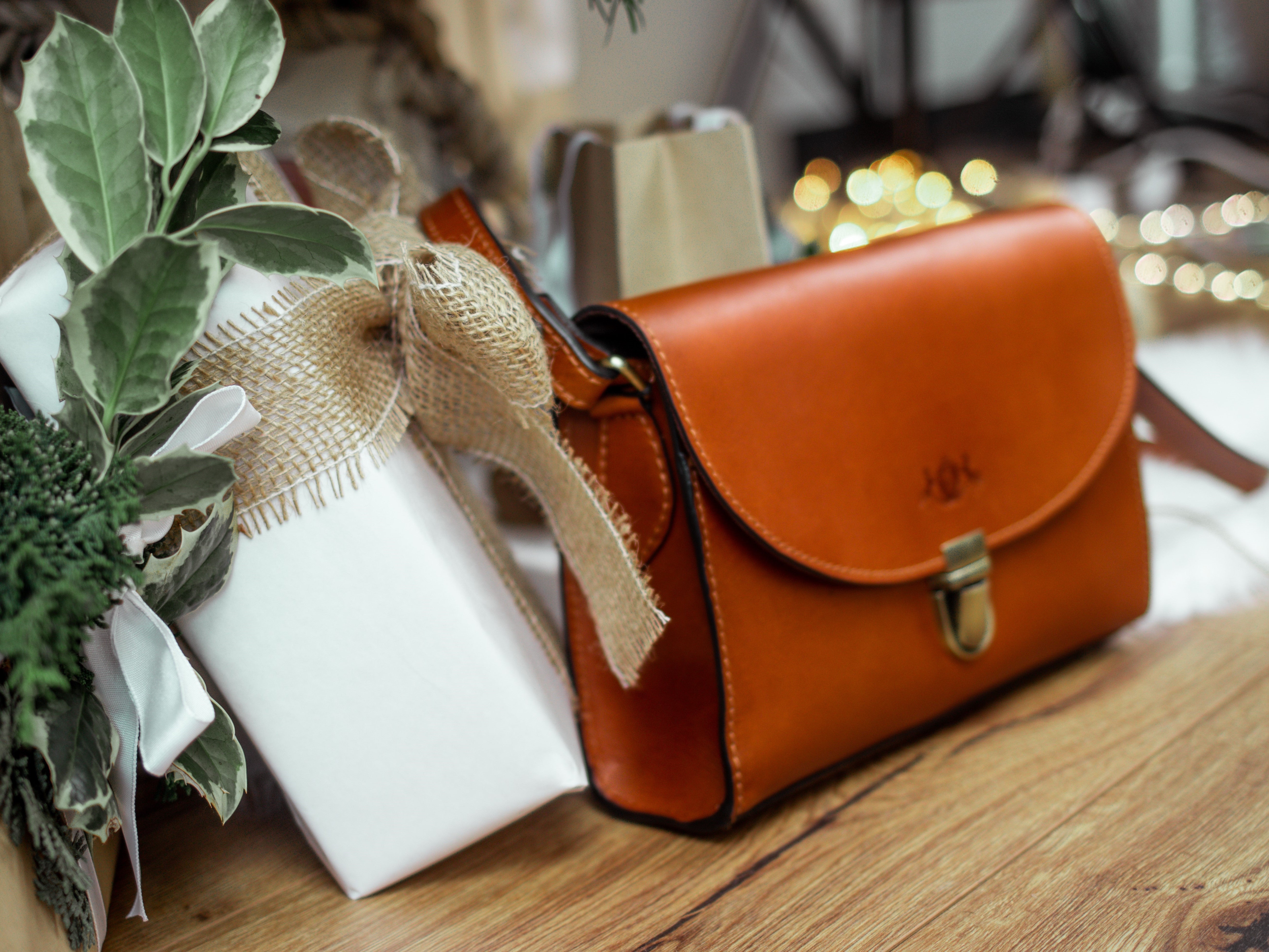 Eine hellbraune Ledertasche von SID & VIN umgeben von Geschenken