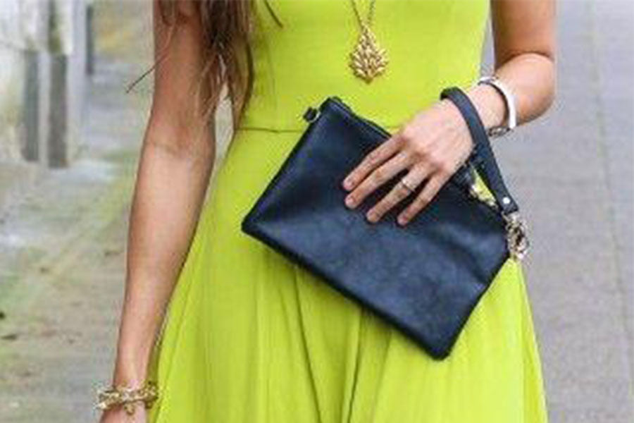 Frau in Neon Grünem Kleid hält kleine Ledertasche