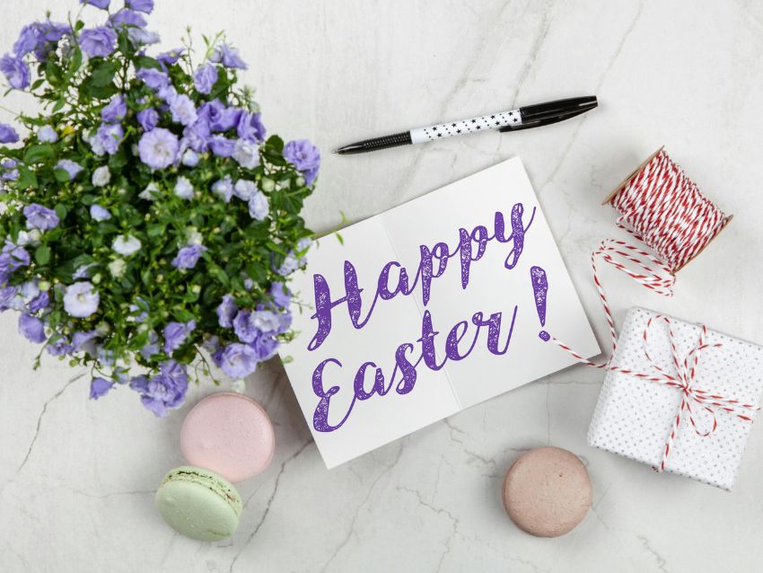 Eine Karte mit den Worten "Happy Easter!", sowie ein Stift, eine Pflanze und ein Geschenk, von oben