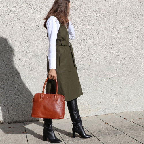 Frau mit Ledertasche, Lederstiefel und grünem Kleid, stehend