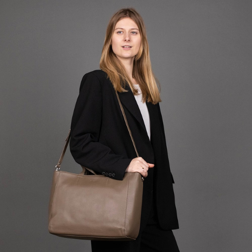 Frau mit brauner Ledertasche über der Schulter von der Seite