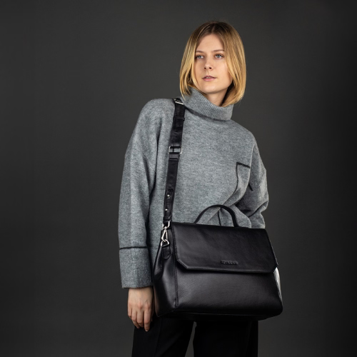 Frau stehend mit schwarzer Ledertasche über der Schulter