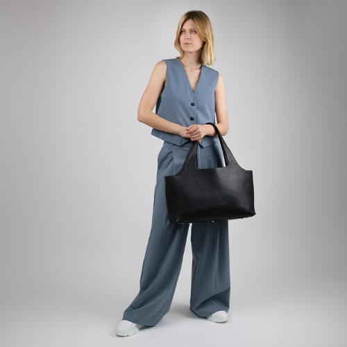 Frau mit schwarzer Ledertasche im Arm von vorne fotografiert