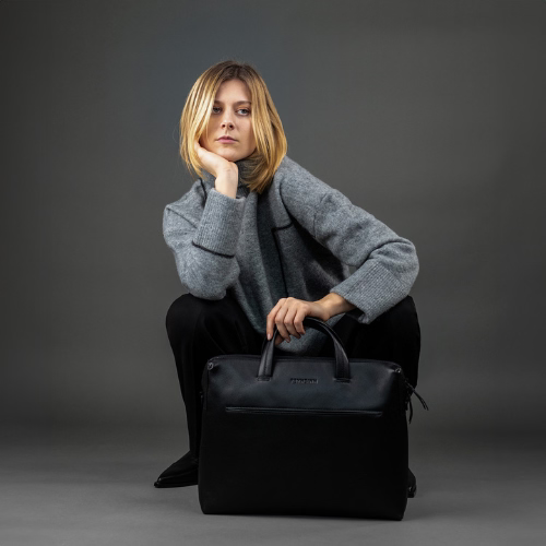 Frau hockend mit schwarzer Ledertasche in einer Hand