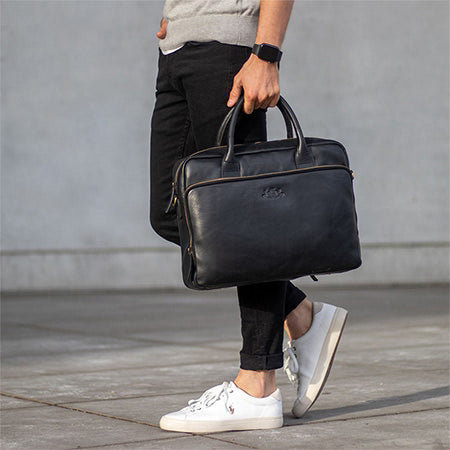 Nahaufnahme einer schwarzen Ledertasche, die in einer Hand getragen wird