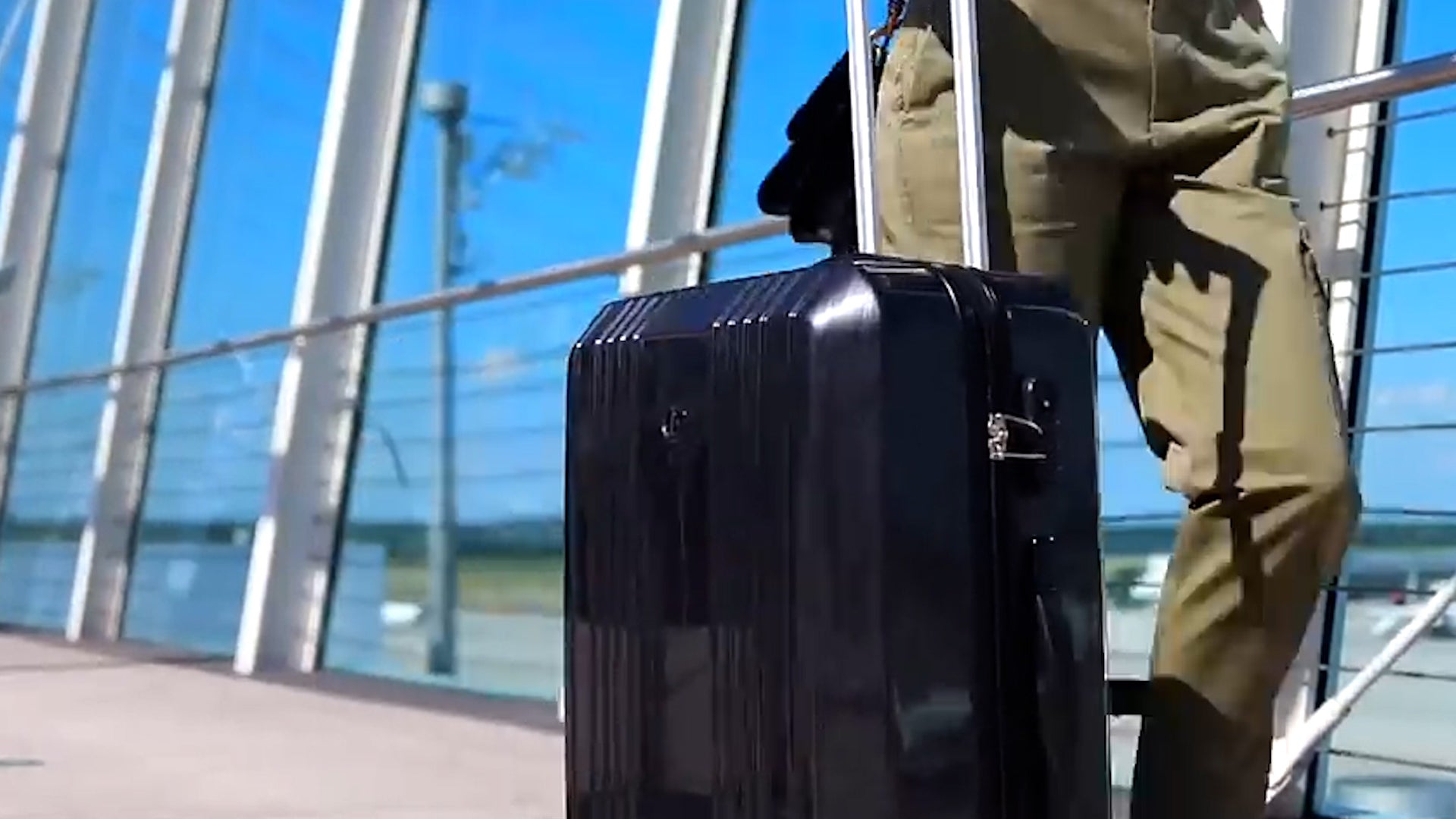 Koffer Cannes im Vordergrund neben Frau am Flughafen