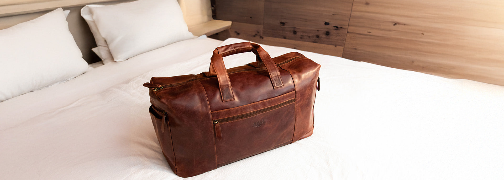 Lederreisetasche mit Patina in braun auf weißem Bett