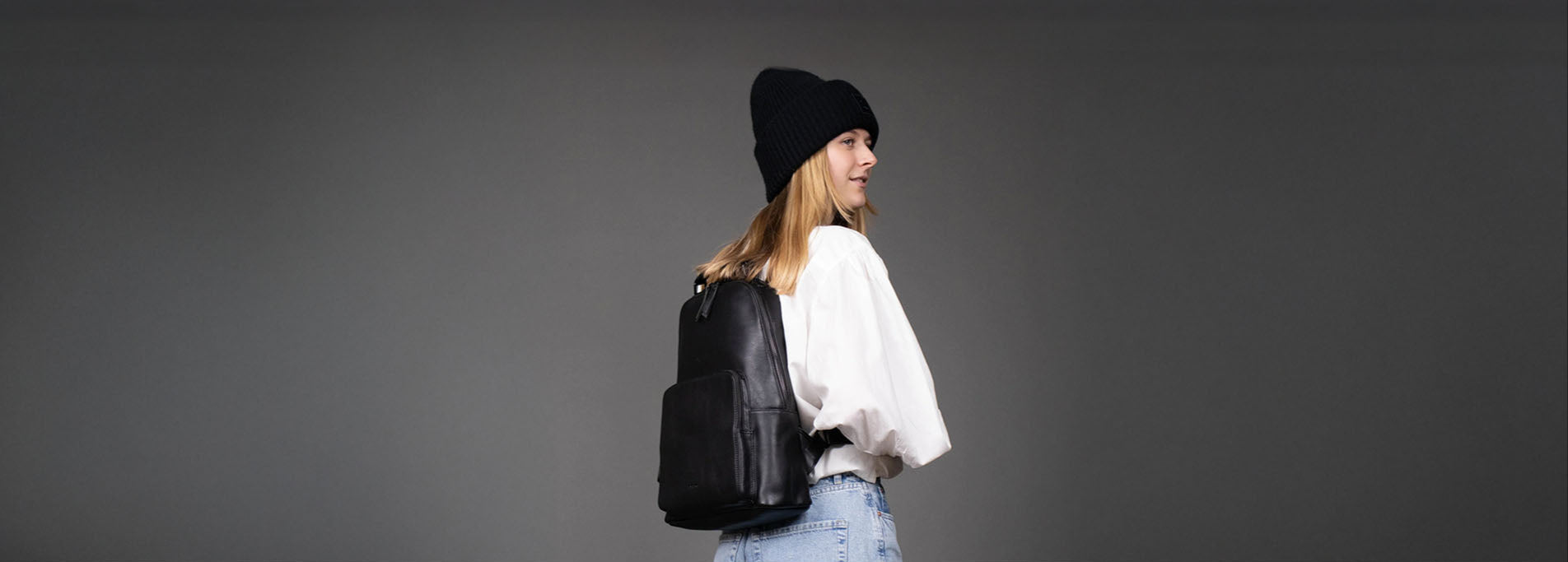 Studiobild blonde Frau mit schwarzen Leder-Rucksack modern