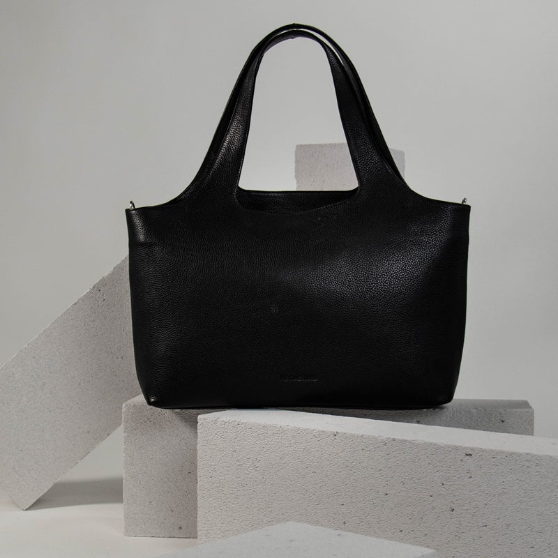Nahaufnahme einer schwarzen Ledertasche auf einem Steinblock