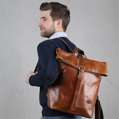 Herren Rucksack Leder Studioaufnahme Mann traegt einen dunkelblauen Pulli mit einer langen Jeans