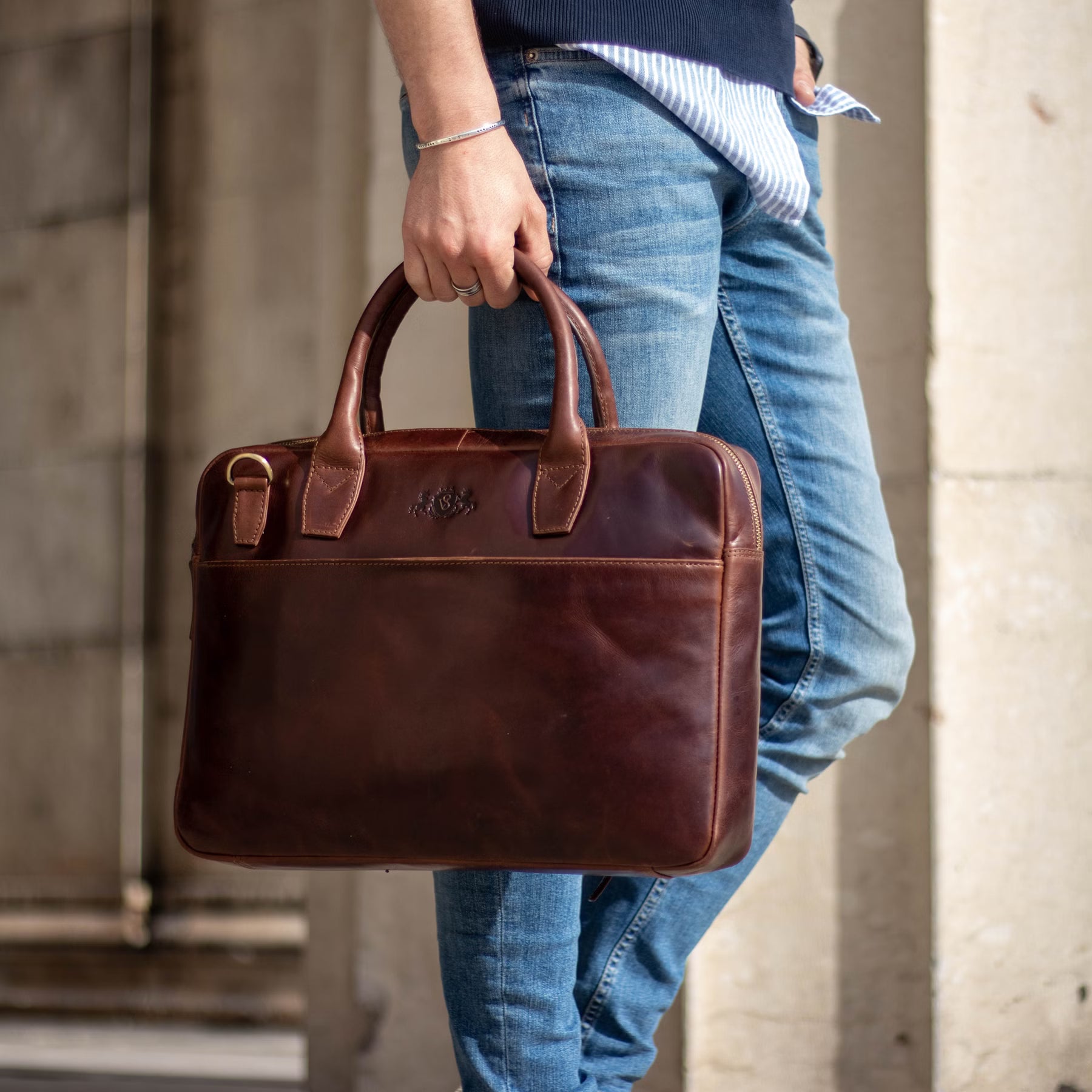 Nahaufnahme einer braunen Ledertasche, getragen von einem Mann