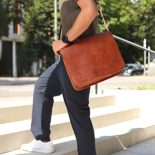 Nahaufnahme einer braunen Ledertasche, die von einem Mann über der Schulter getragen wird