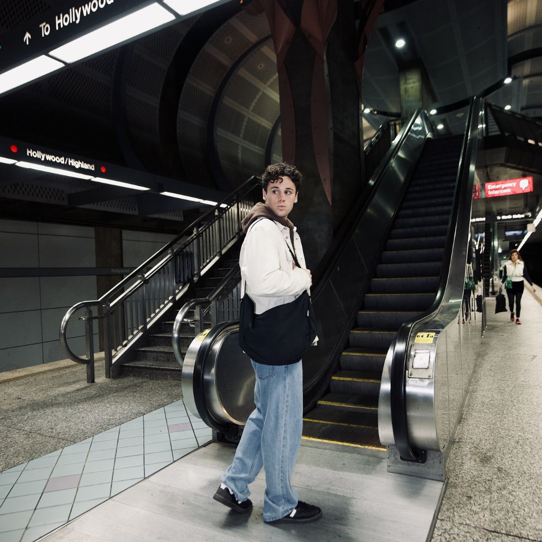 Moon Bag XL schwarz moodbild outdoor mann steht an der rolltreppe traegt weiße jacke