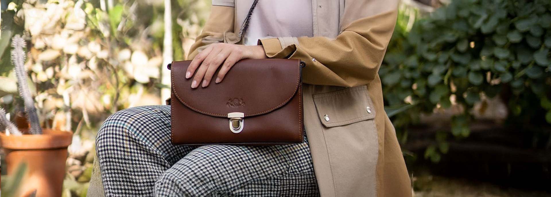 Sattelleder Schultertasche auf Schoß von Frau in Gewächshaus