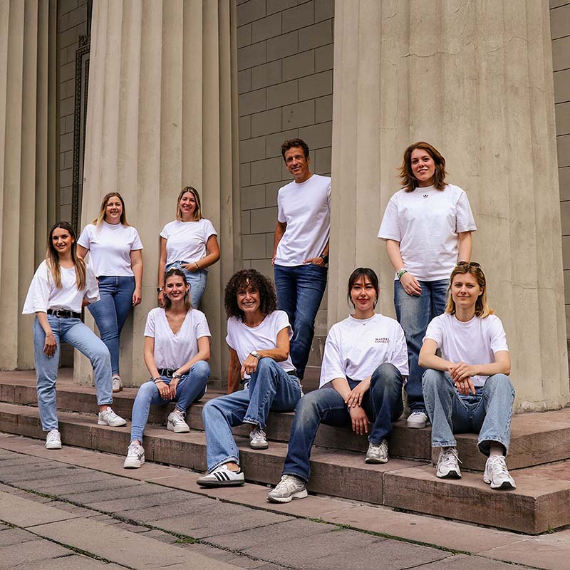 Teamfoto Kopenhagen myBagfactory Personen sitzen auf Treppe vor Säulen