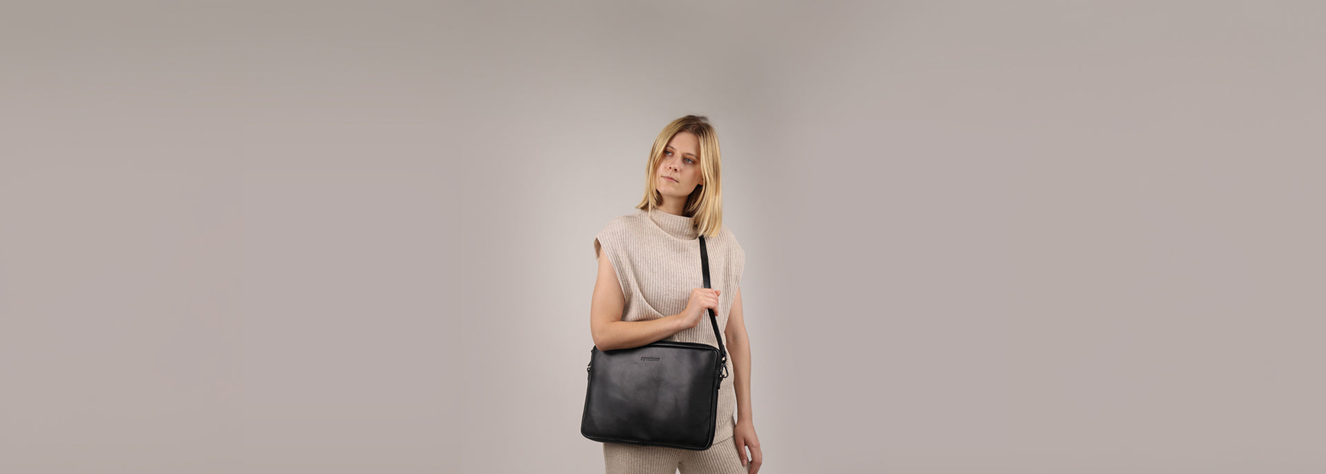 Studiobild mit weiblichen Model in beigen Outfit und schwarzer Glattleder Arbeitstasche für Frauen