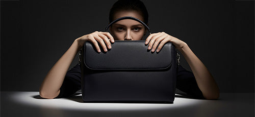 Wir sehen eine attraktive Managerin mit ihrer Laptoptasche für Damen aus schwarzem Leder