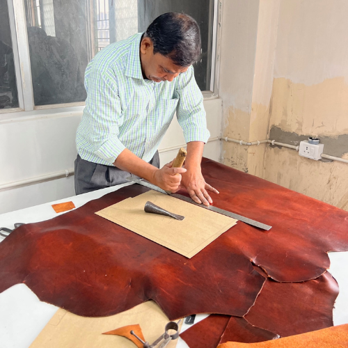 Ein Mann schneidet ein großen Stück leder zurecht