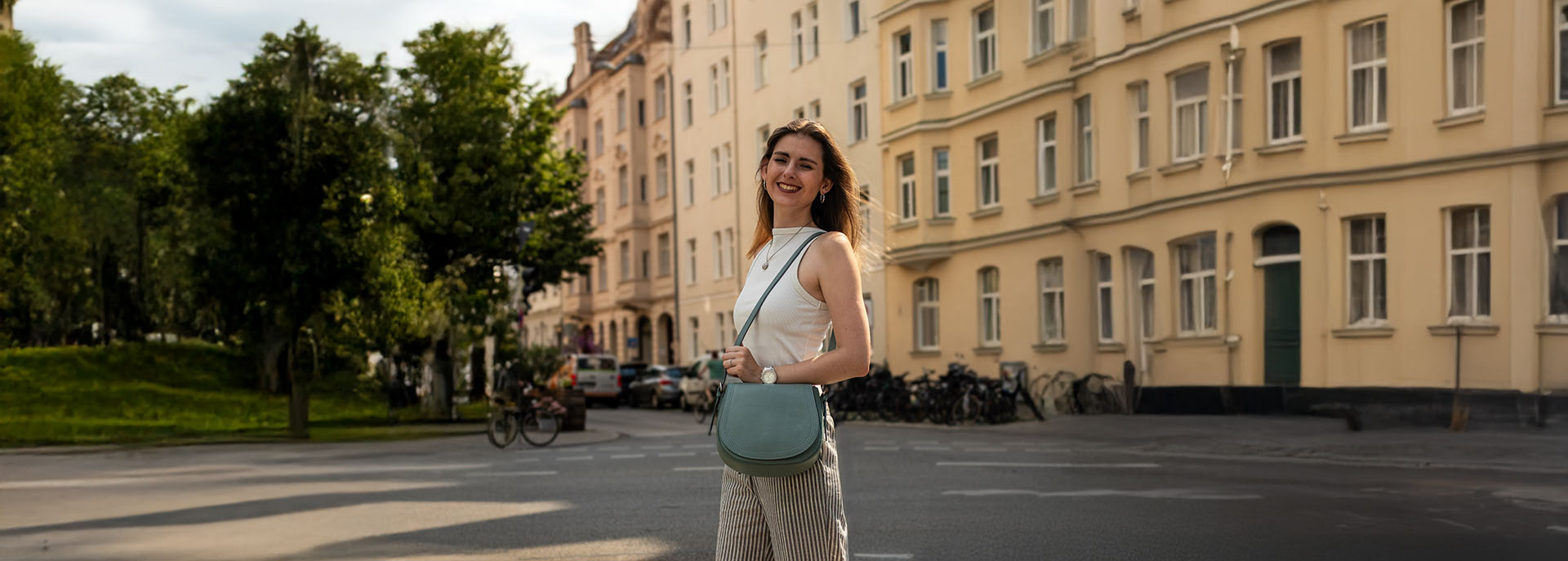 Frau steht ind er Stadt mit blauer Ledertasche
