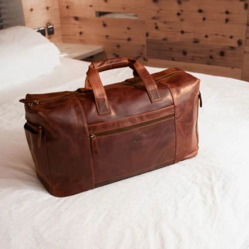 Reisetasche Leder braun steht im Hotelzimmer auf dem Bett
