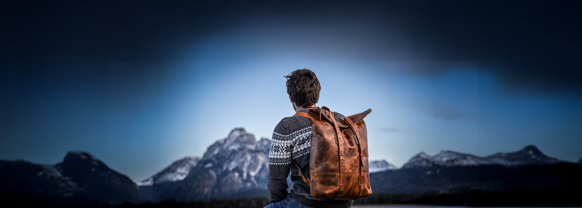 Mann mit Rucksack aus Leder vor Skyline der Berge im Allgäu