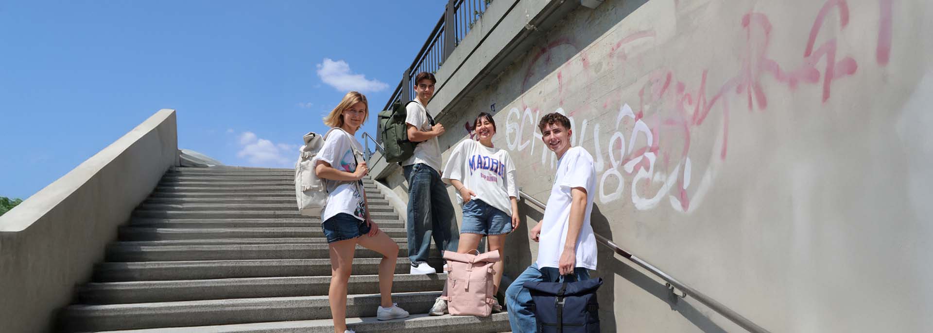 Universität mit Freundesgruppe. Jeder hat einen Roll-Top Rucksack an