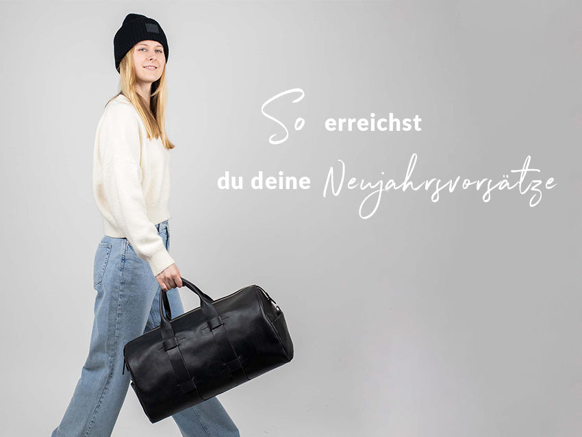 Model mit dem FEYNSINN Weekender TROY aus Leder in schwarz, mit dem Header Text "So erreichst du deine Neujahresvorsätze"