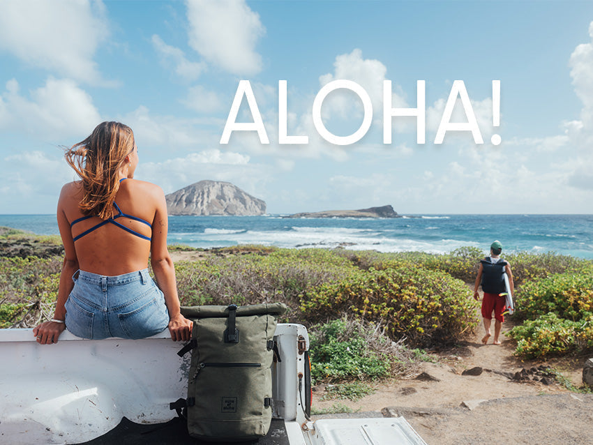 Eine Frau und eine Mann vor einem Strand mit dem Header Text "ALOHA!"