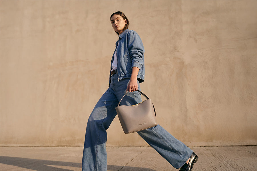 Helle Hobo Bag klein in der Hand einer Frau in einem Jeans-Outfit. 