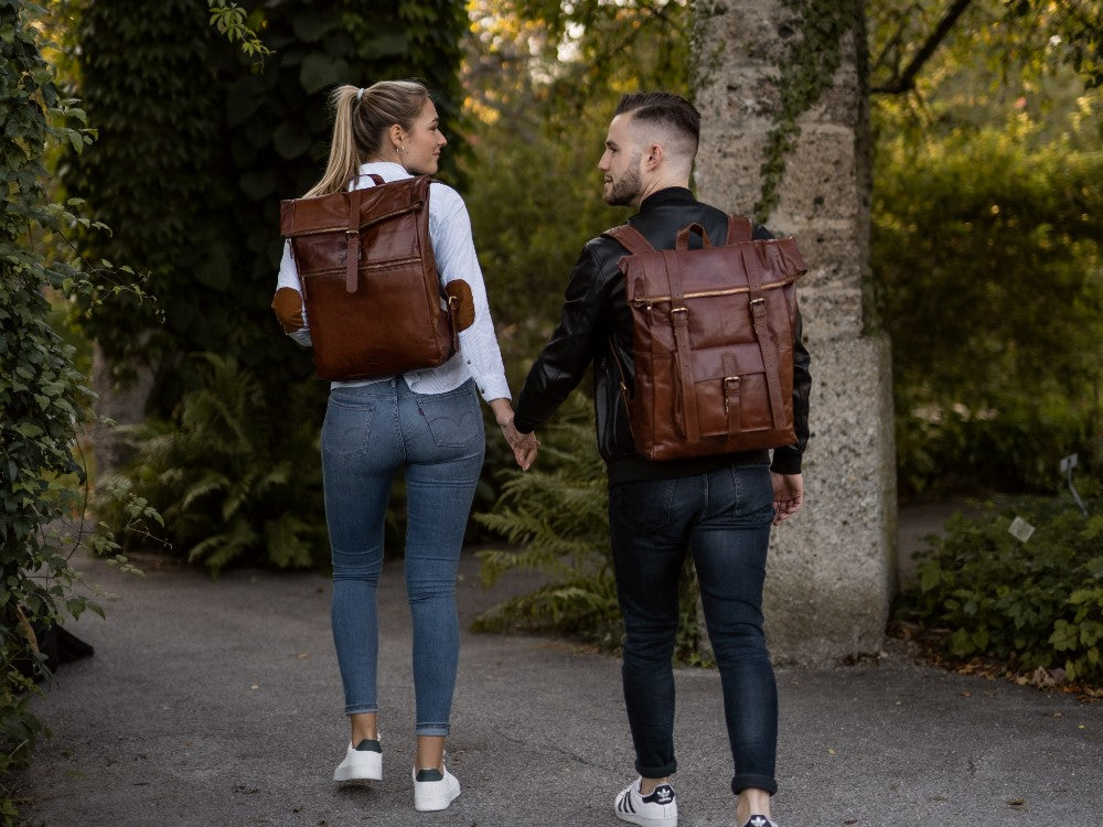 Frau und Mann mit braunen Lederrucksäcken in einem Wald