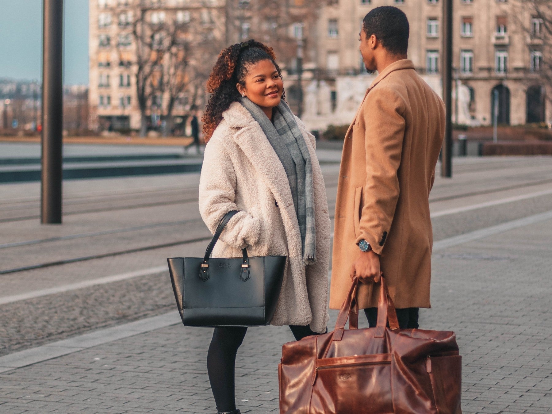 Eine Frau und ein Mann mit jeweils einer Ledertasche in der Hand