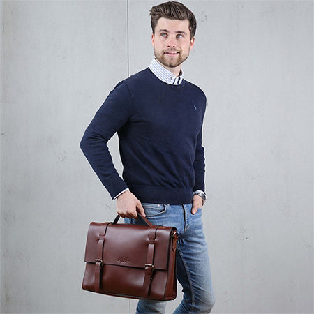 Mann stehend, mit brauner Ledertasche in der Hand