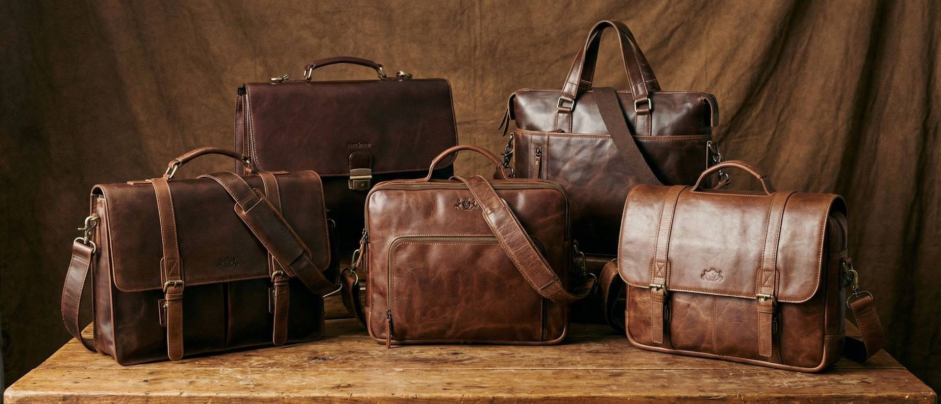 Fünf Aktentaschen stehen nebeneinander auf einem Holztisch