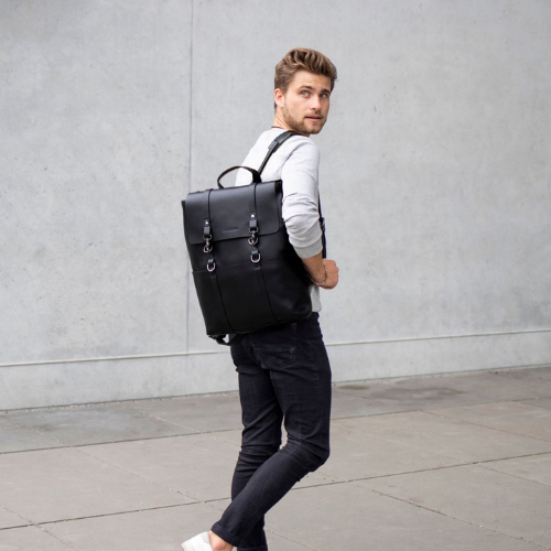 Mann mit schwarzen Laptoprucksack über der Schulter blickt zurück über seine Schulter