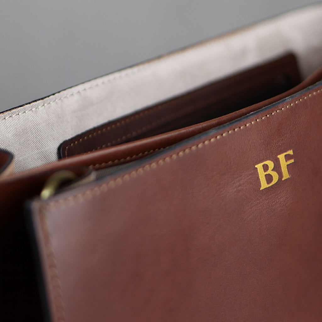Innenseite einer braunen Ledertasche mit Prägung in gold