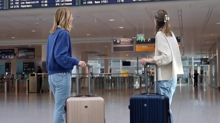 Zwei Frauen mit Hartschalenkoffer am Flughafen
