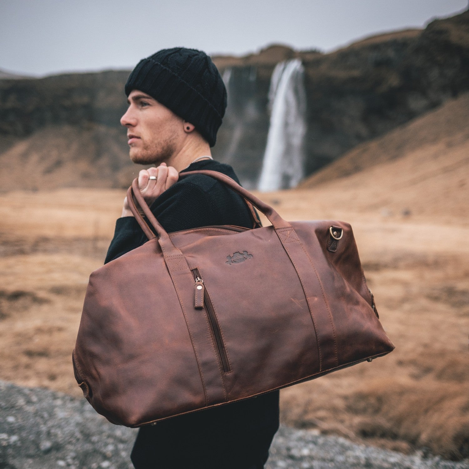 Reisetasche Aus Leder Mann traegt die Reisetasche lässig über der Schulter in Island