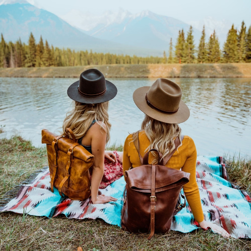 Rolltop Rucksack Damen zwei Frauen sitzen am Fluß und tragen einen HUt