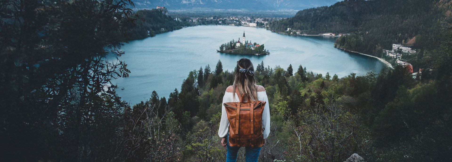 Roll-Top Rucksack aus Leder auf Rücken von Mädchen beim Wandern. Blick auf einen See