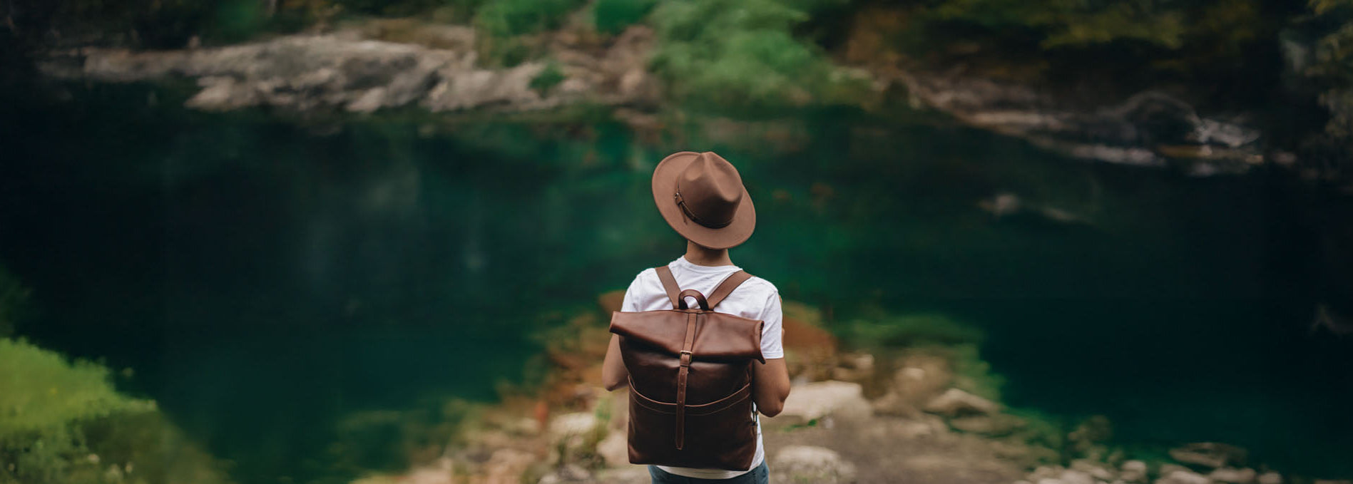 Roll Top Rucksack aus Leder an Mann vor einem klaren See