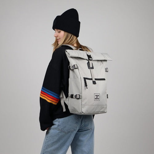 Studioaufnahme grauer Hintergrund Model traegt Reiserucksack Damen und einen schwarzen Pulli und eine schwarze Mütze