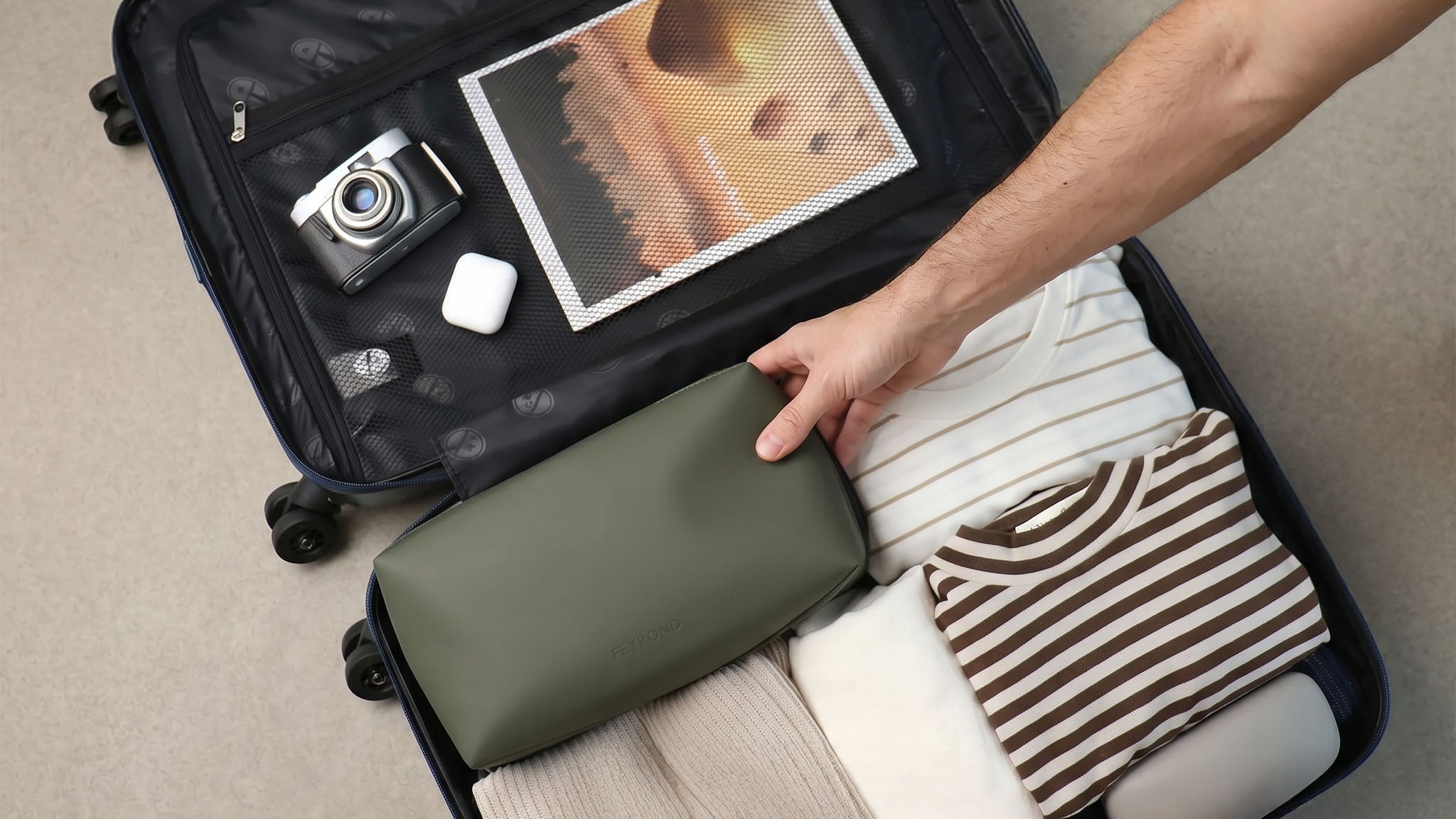 Ein Koffer wird mit Klamotten und einer kleinen Tasche bepackt