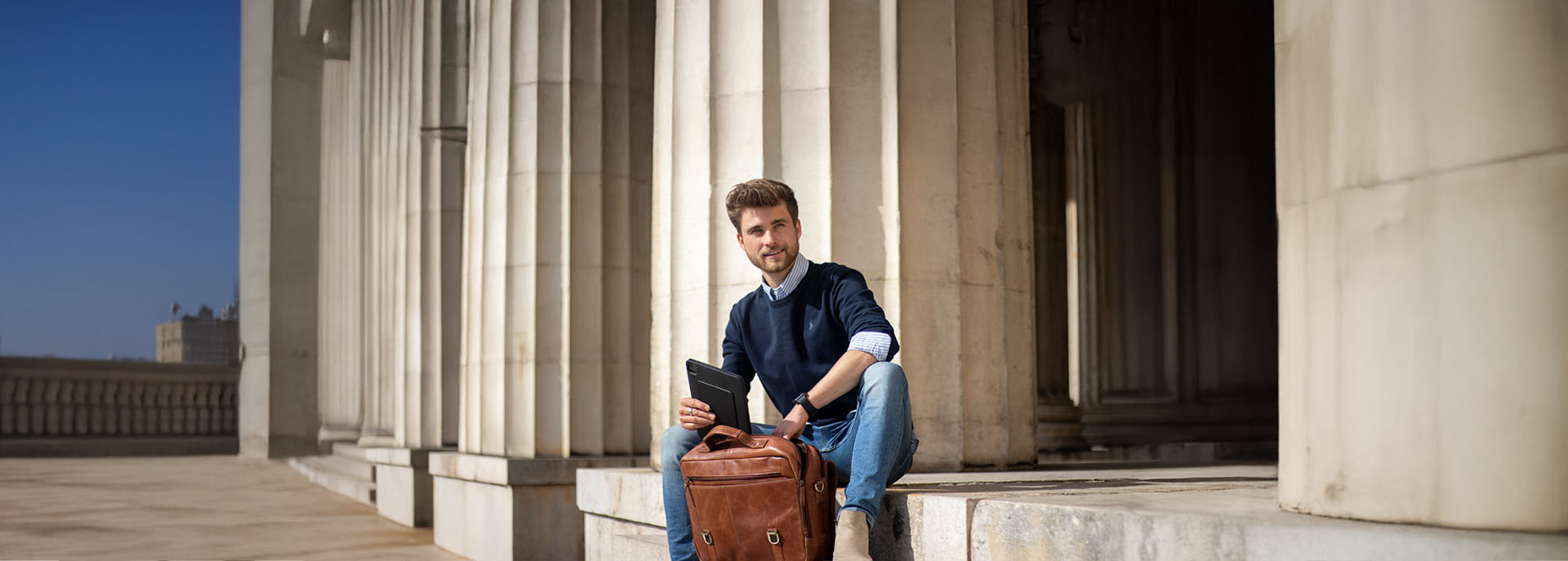 Mann mit Tablet in der Hand und Laptoptasche