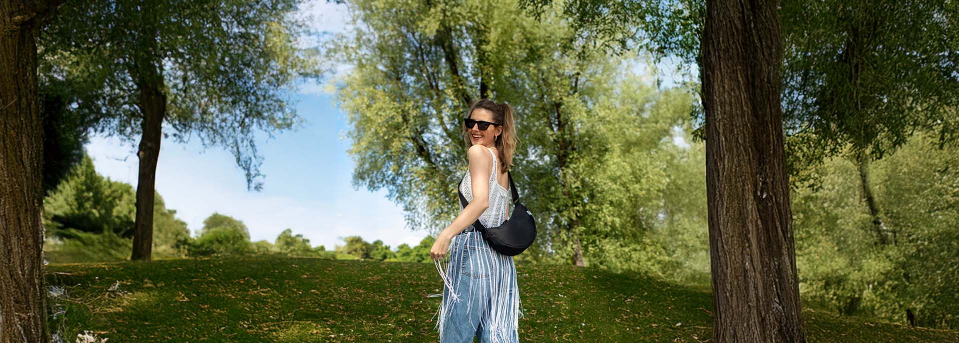 Frau mit schwarzer Tasche auf dem Weg zum Festival geht einen Hügel hoch