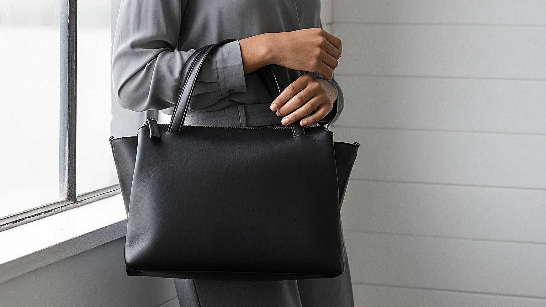 hübsche frau mit einer damentasche aus schwarzem leder in einem loft