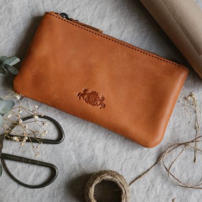 Geschenkefinder Etui aus Leder in hellbraun auf einem Tisch und Geschenkverpackungsmaterial