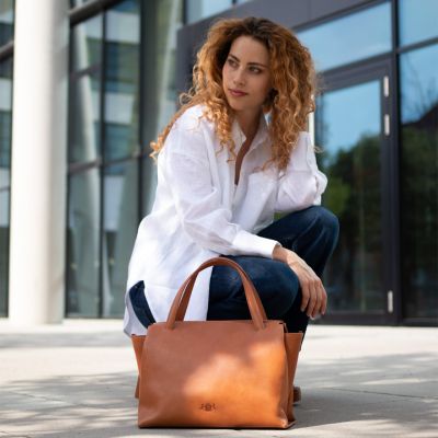 Handtasche Damen aus Leder in hellbraun Frau traegt eine weiße Bluse