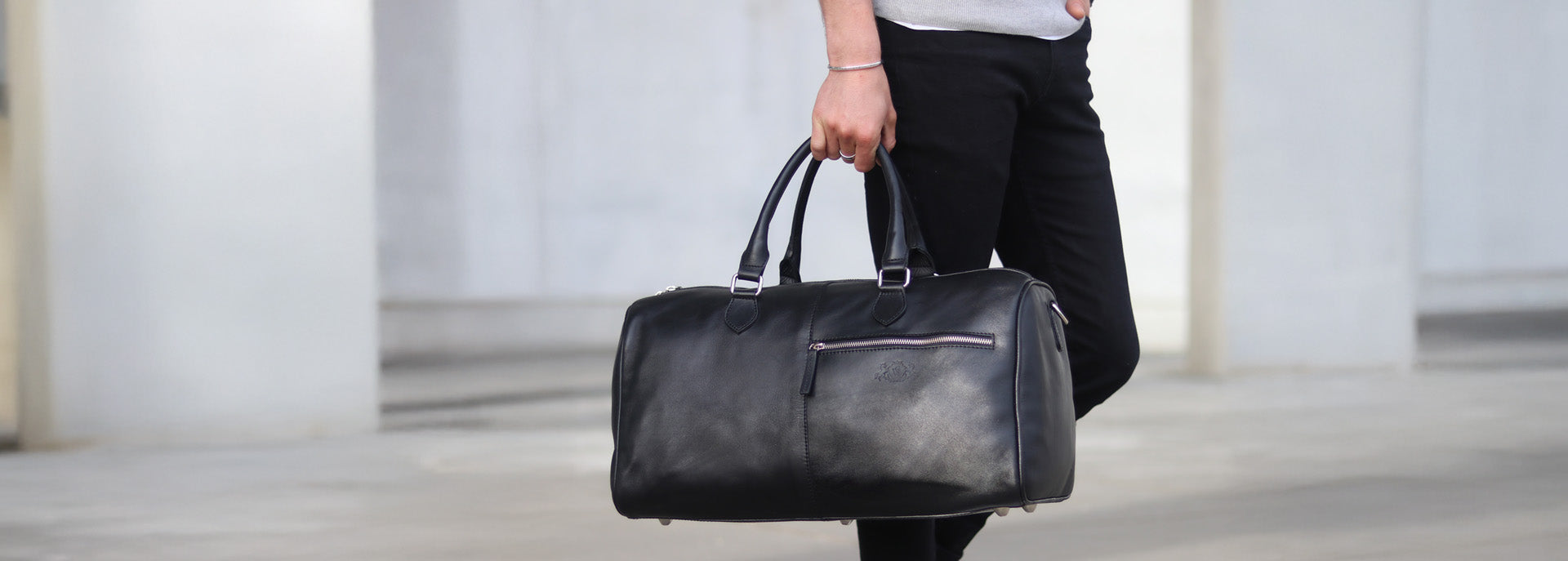 Weekender Leder schwarz in Hand eines Mannes in der Stadt